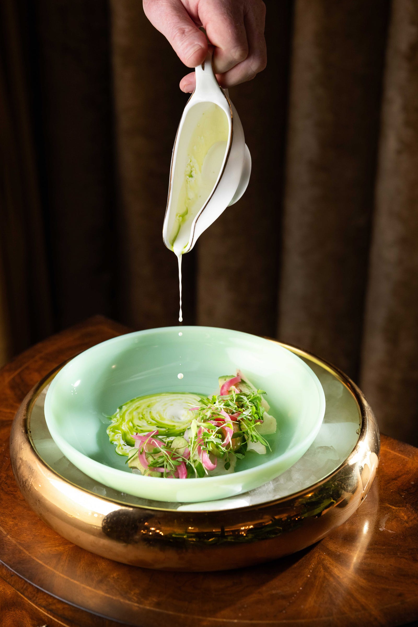 A Delilah Dallas dish being finished with green sauce